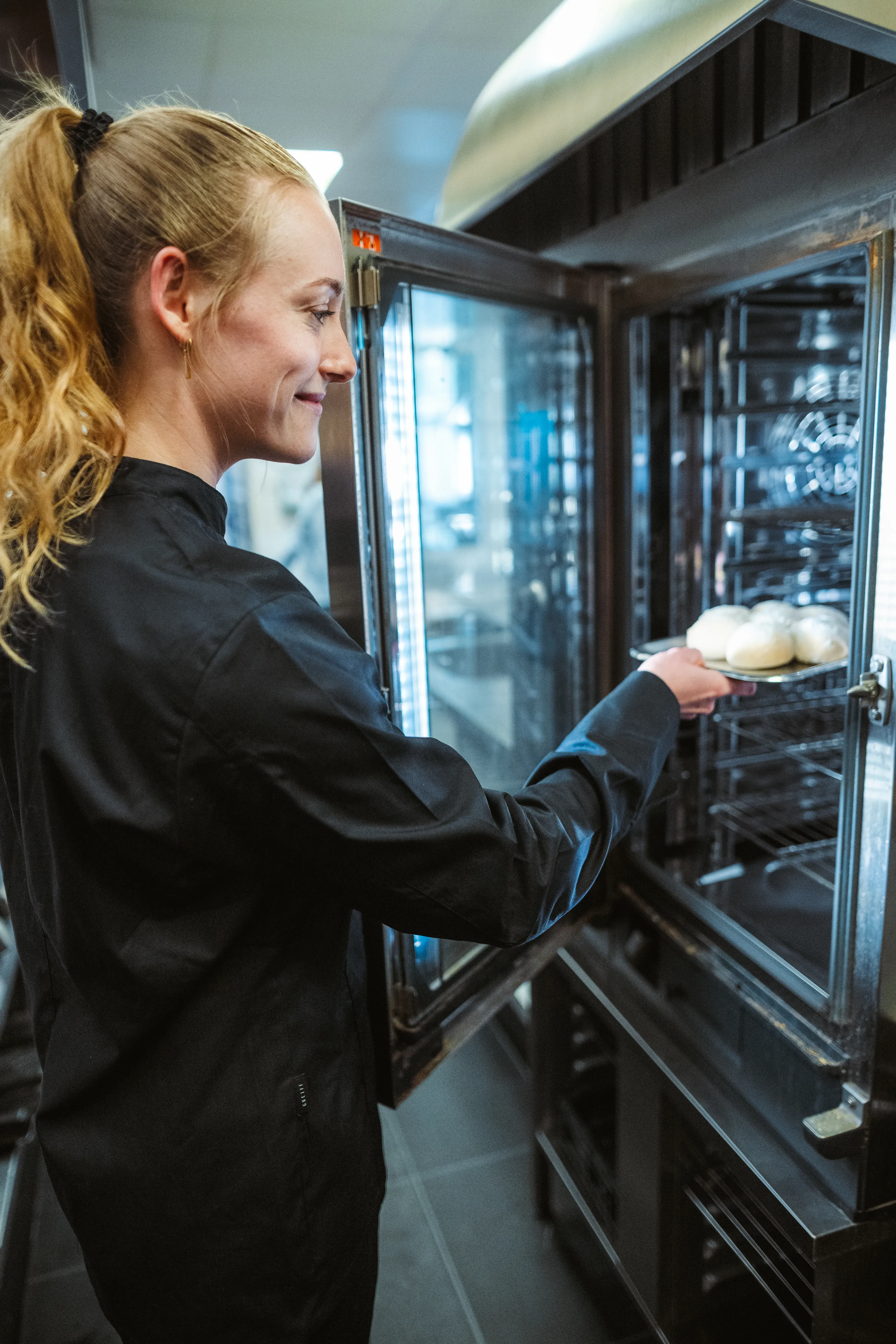 Vrouwelijke medewerker schuift een gerecht in de oven