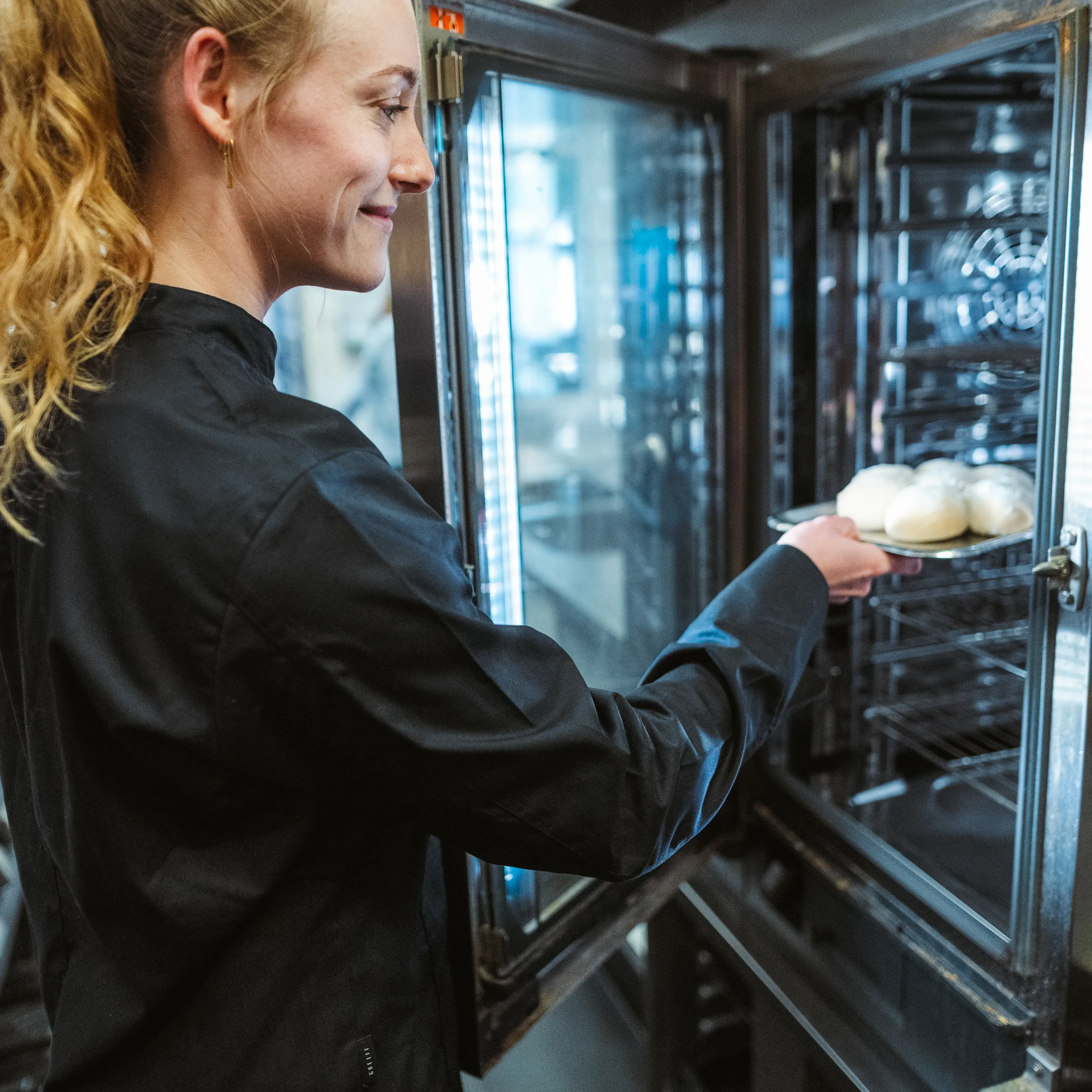 Vrouwelijke medewerker schuift een gerecht in de oven